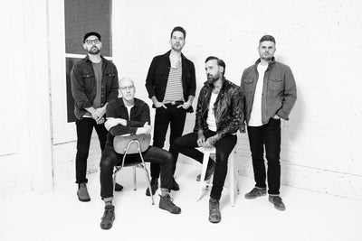 Black and white photo of a group of five men of the band Acceptance posing indoors.