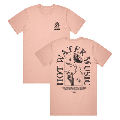 pink t shirt. The top right has a small campfire graphic. The back of the shirt has the band name "HOT WATER MUSIC" arched around a hand holding a rose. There is also very small text underneath the main design that is unreadable in the photo.