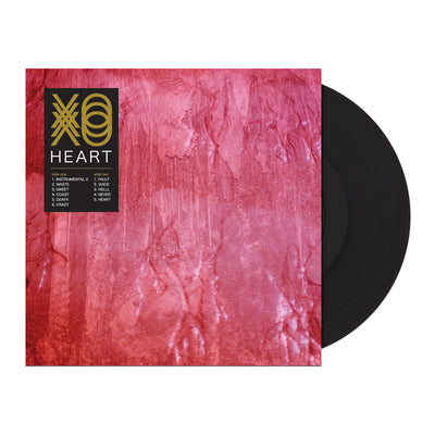 Record against white background. Vinyl is black. Jacket is a pink marbled background with a black rectangle in the upper left corner. The rectangle has "XO" printed in gold. There are 3 of each letter printed and they are layered on top of each other. Below is printed "HEART" and the track list is printed below that. 