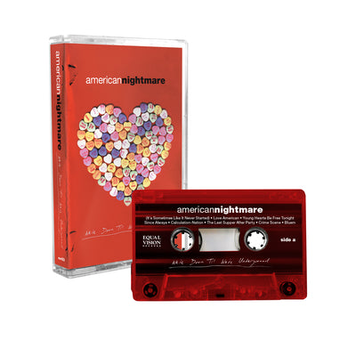 American Nightmare - 'We're Down Til We're Underground' cassette. Against a white background, a translucent red cassette tape with the words "americannightmare" in white and 'We're Down Til We're Underground" below them in white cursive letters. Behind the tape is the case, which is red with the words "american" in white and "nightmare" in black on top. Below it is a heart composed of multi-colored candy hearts. below the heart are the words "We're Down Til We're Underground" in white cursive.