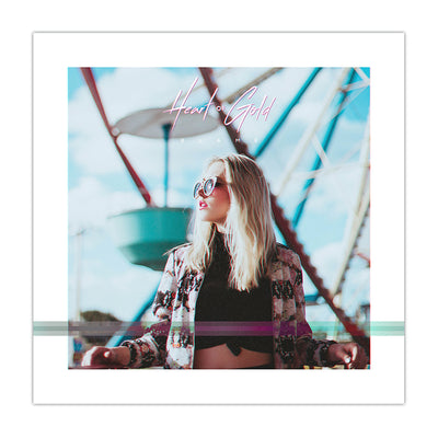 Image of a girl wearing sunglasses and standing in front of a ferris wheel. There is text above the girl that says HEART OF GOLD in pink font, and below that there is text that says BLAME.