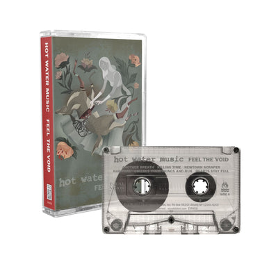 Cassette tape with artwork of a woman wearing a long grey dress in the center. The woman is reaching down onto her legs where there is a deer that has been split in half. In each corner is drawings of light pink flowers, one of them having a skull blooming out of it. On the bottom there is text that lightly says HOT WATER MUSIC and below it there is text that says FEEL THE VOID. To the right is a clear cassette with the same text written on it.