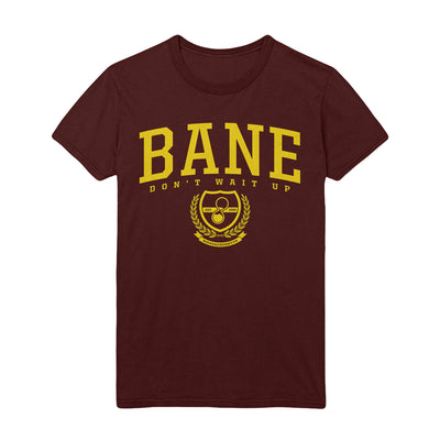 Maroon t-shirt with the text "BANE" printed in bold yellow color in the top center. Right below is the text "DON'T WAIT UP" in same yellow color. Below that is a emblem of an hourglass with leaves on either side in same yellow color.