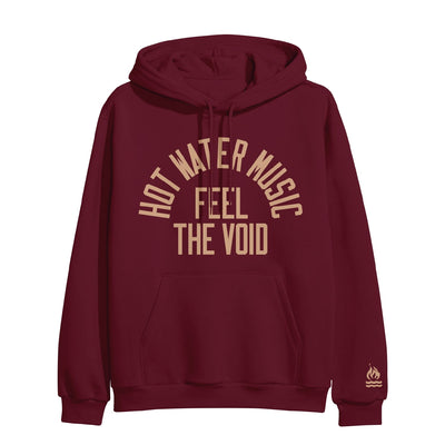 Maroon colored pullover hoodie with HOT WATER MUSIC written across the chest in a half circle. Below that there is text that says FEEL THE VOID. On the bottom of one sleeve, there is a drawing of a fire with two lines underneath it representing water.