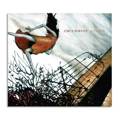 Square CD with text that says CIRCA SURVIVE JUTURNA in the top right. The artwork is a girl wearing a dress and walking through grass with her hair blowing in the wind. On the right there is a brick building and a black gate.