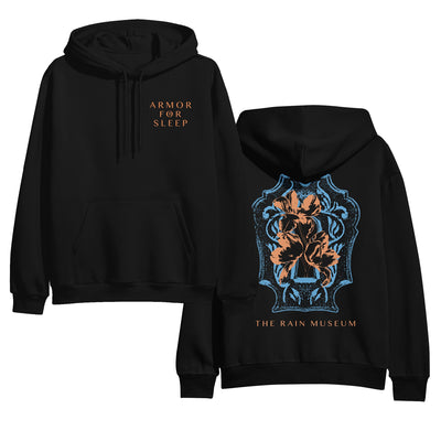 Black pullover hoodie with ARMOR FOR SLEEP written in orange text in the top corner of the chest. The back of the hoodie is a blue and orange colored crest design with THE RAIN MUSEUM written in orange text below it.